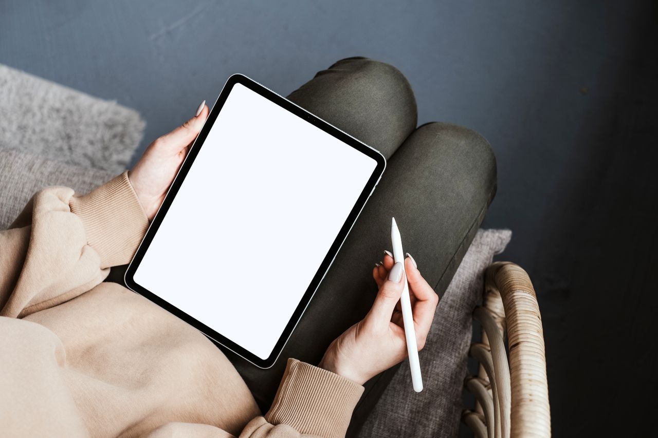 Mastering the First Impression: Your intriguing post title goes here A person using a tablet with a stylus in a cozy, relaxed indoor setting on a chair.